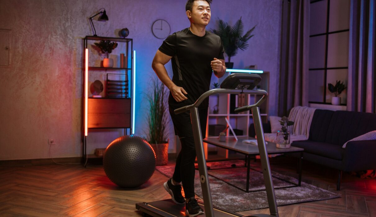 Attractive young sports asian man doing fitness exercise, running on treadmill .