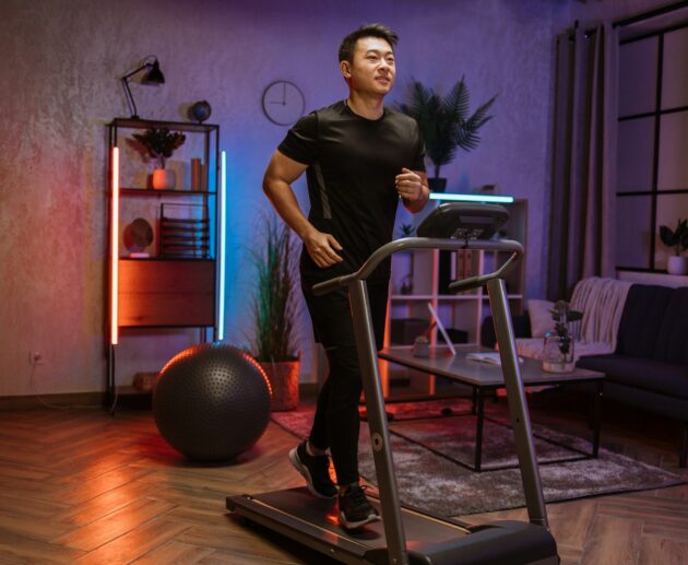 Attractive young sports asian man doing fitness exercise, running on treadmill .