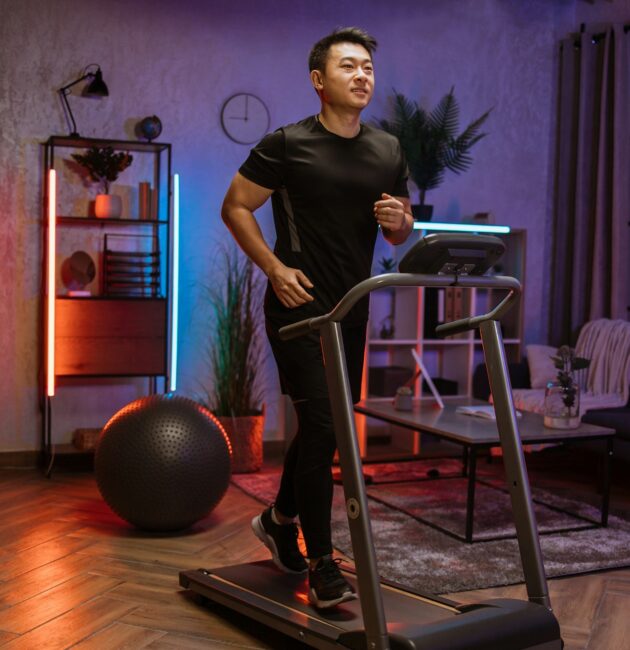 Attractive young sports asian man doing fitness exercise, running on treadmill .