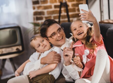 cheerful 1950s style family taking selfie with smartphone at home