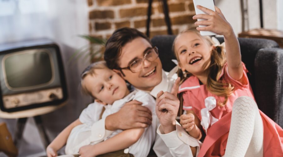 cheerful 1950s style family taking selfie with smartphone at home