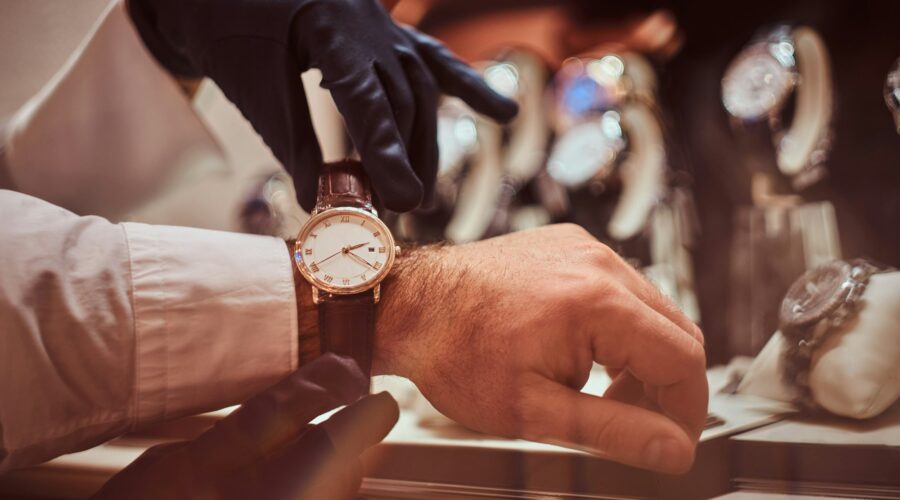 Close-up hands. Assistant helps the client to try on exclusive men's watches.