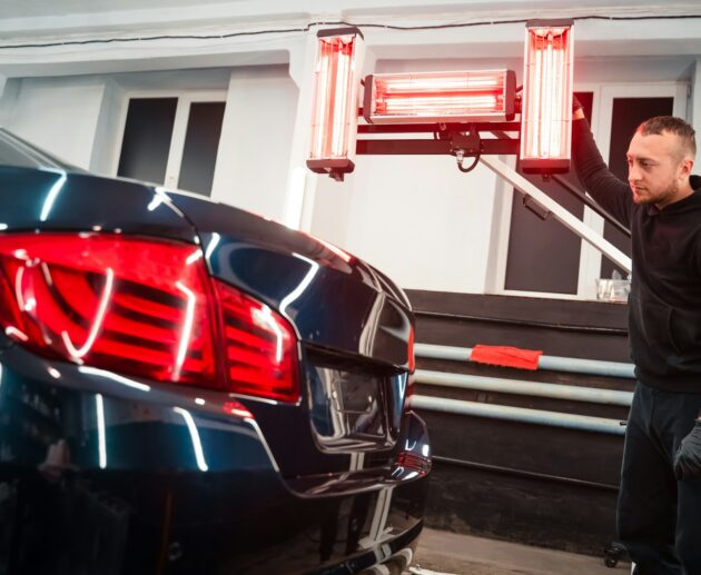 Detailing worker with infrared lamps near the car. Car detailing concept