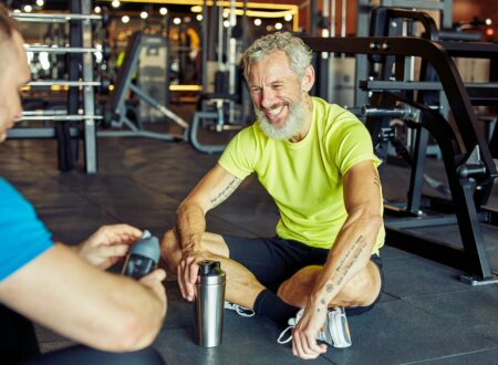 Exercising with personal trainer. Happy middle aged man discussing something with fitness