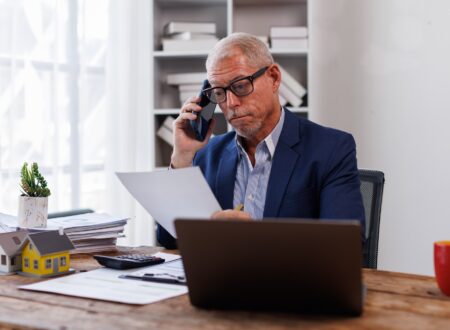 house model on workplace desk with real estate agent professional making business call talking on mo