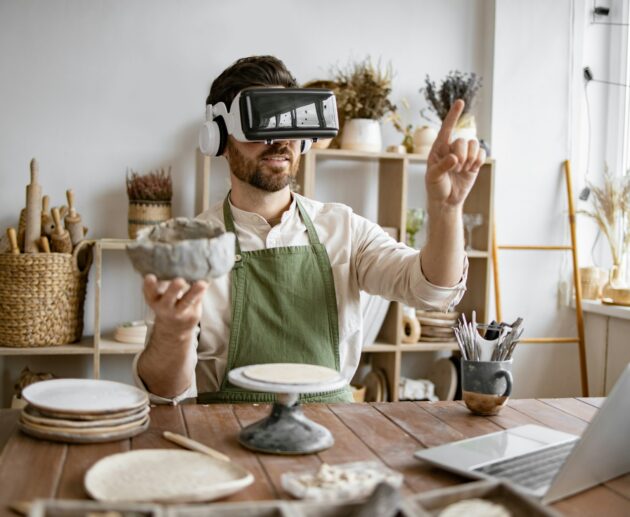 Man using virtual reality glasses to sculpt pottery in studio