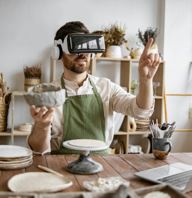 Man using virtual reality glasses to sculpt pottery in studio