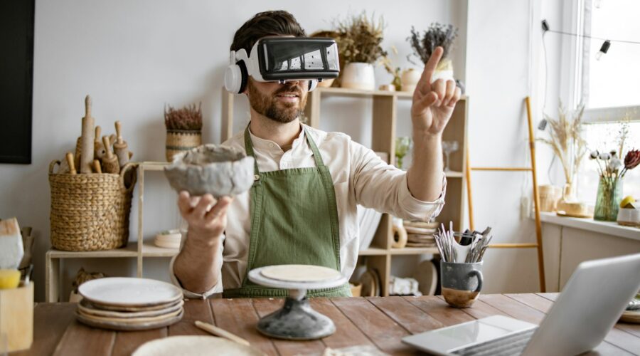 Man using virtual reality glasses to sculpt pottery in studio