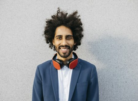 Portrait of smiling young businessman with headphones at a wall