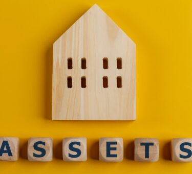 The word assets written on wooden cubes with assets icon on yellow background. Asset management