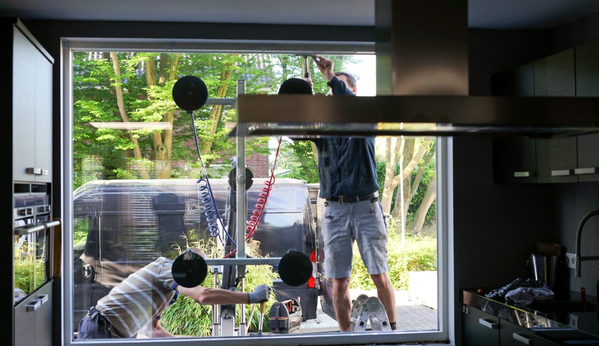 Window installers removing old, inefficient windows from a home during home improvement project.