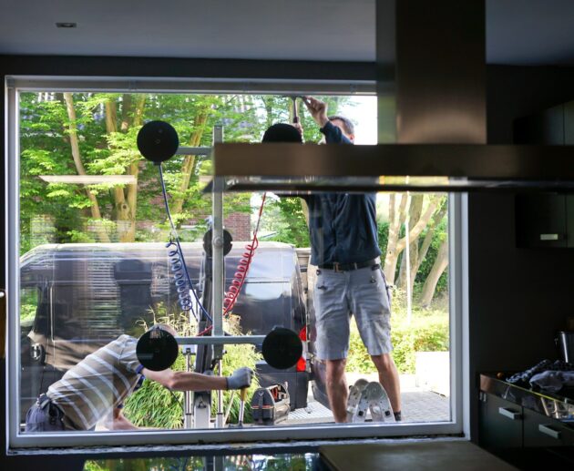 Window installers removing old, inefficient windows from a home during home improvement project.