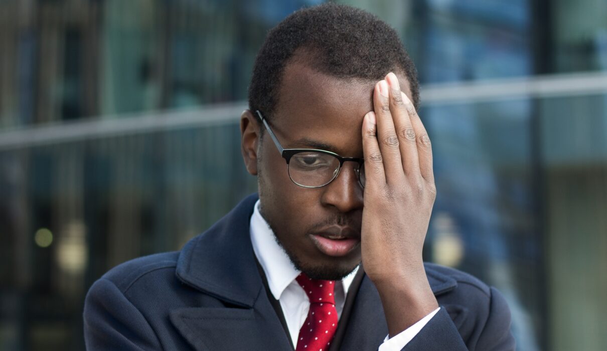 Young African American businessman looks extremely troubled, confused and tired