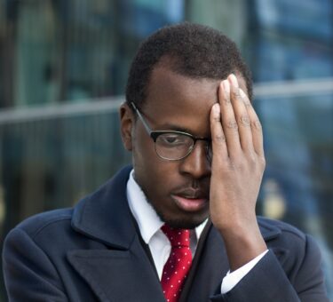 Young African American businessman looks extremely troubled, confused and tired