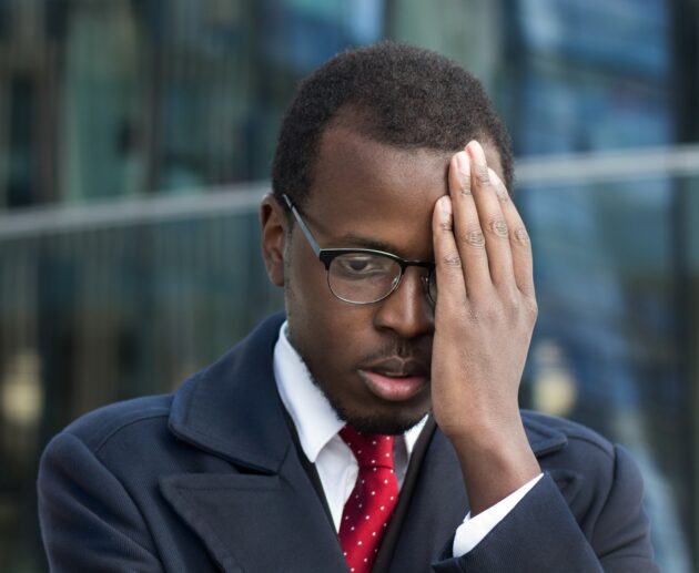 Young African American businessman looks extremely troubled, confused and tired