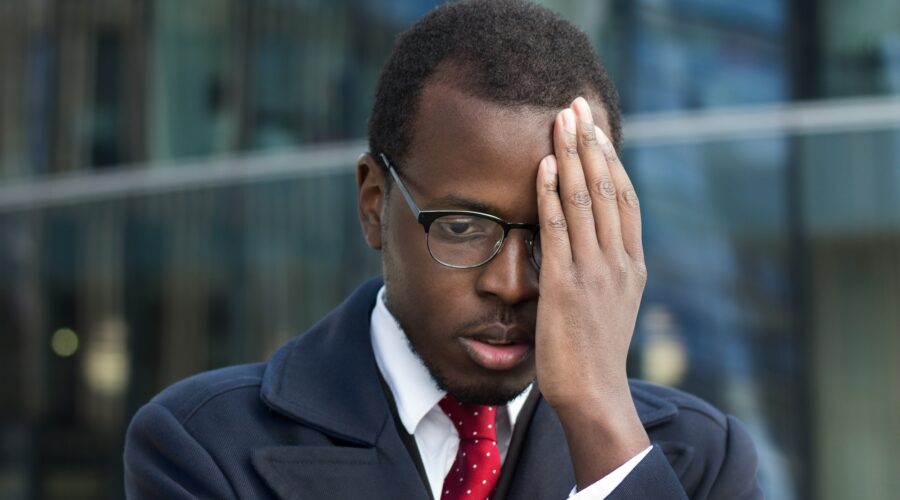 Young African American businessman looks extremely troubled, confused and tired