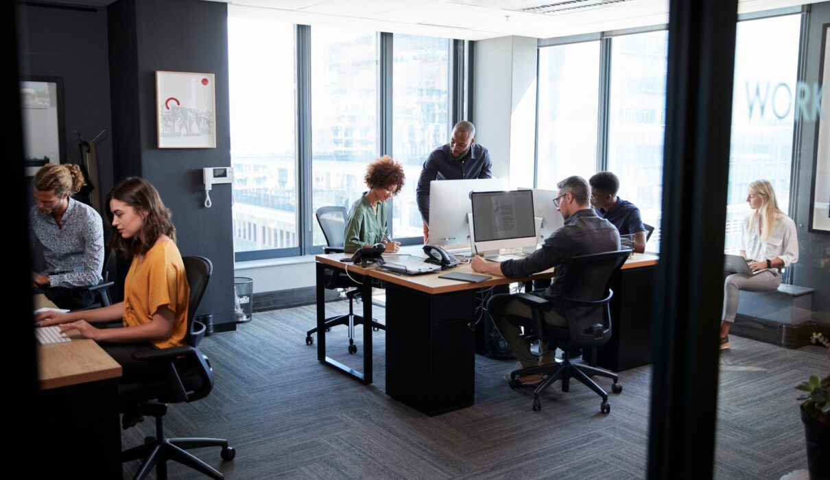 Young creative team working together at computers in a casual office, seen from doorway