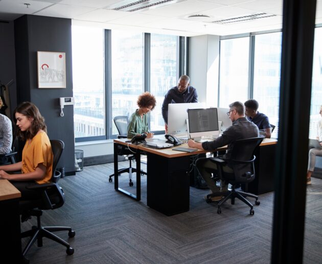 Young creative team working together at computers in a casual office, seen from doorway