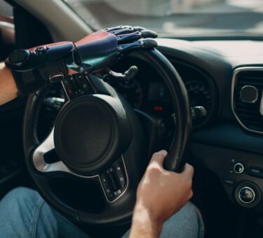 Young disabled man driver with artificial prosthetic hand driving vehicle car.