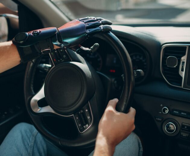 Young disabled man driver with artificial prosthetic hand driving vehicle car.